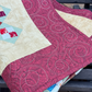 Folded scrappy 4-patch quilt displaying quilted texture and rich autumn colors on a wooden bench