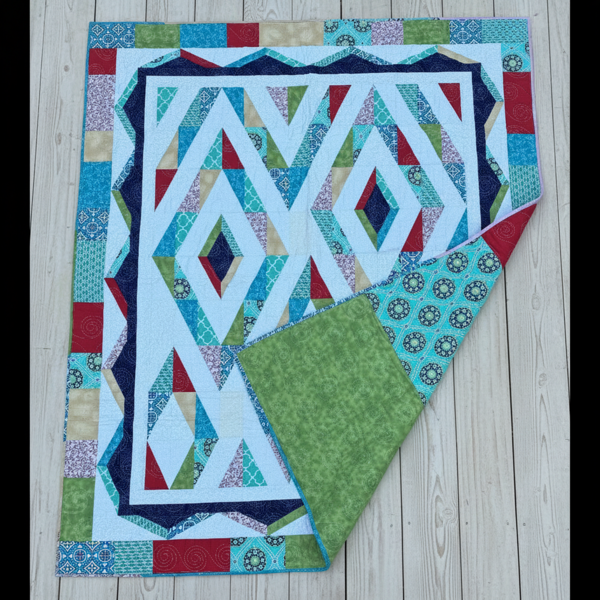 Prism quilt showing front geometric design and coordinating patchwork backing