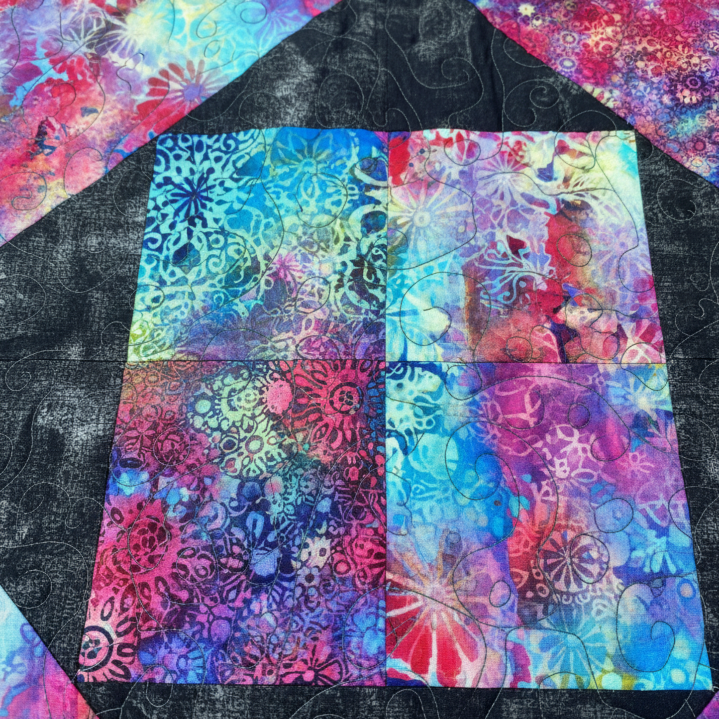 Colorful quilt block with abstract patterns on a black background. 