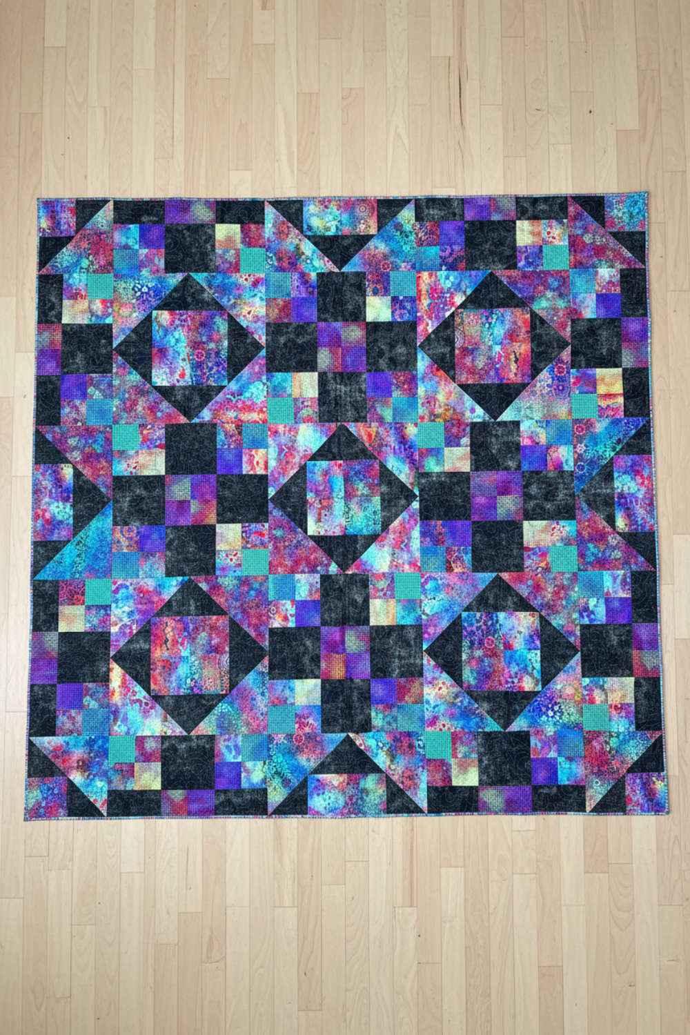 Handmade Jewels of the Night quilt laid flat showing jewel-toned patchwork design