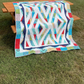 Prism quilt displayed as a throw over wooden picnic table outdoors