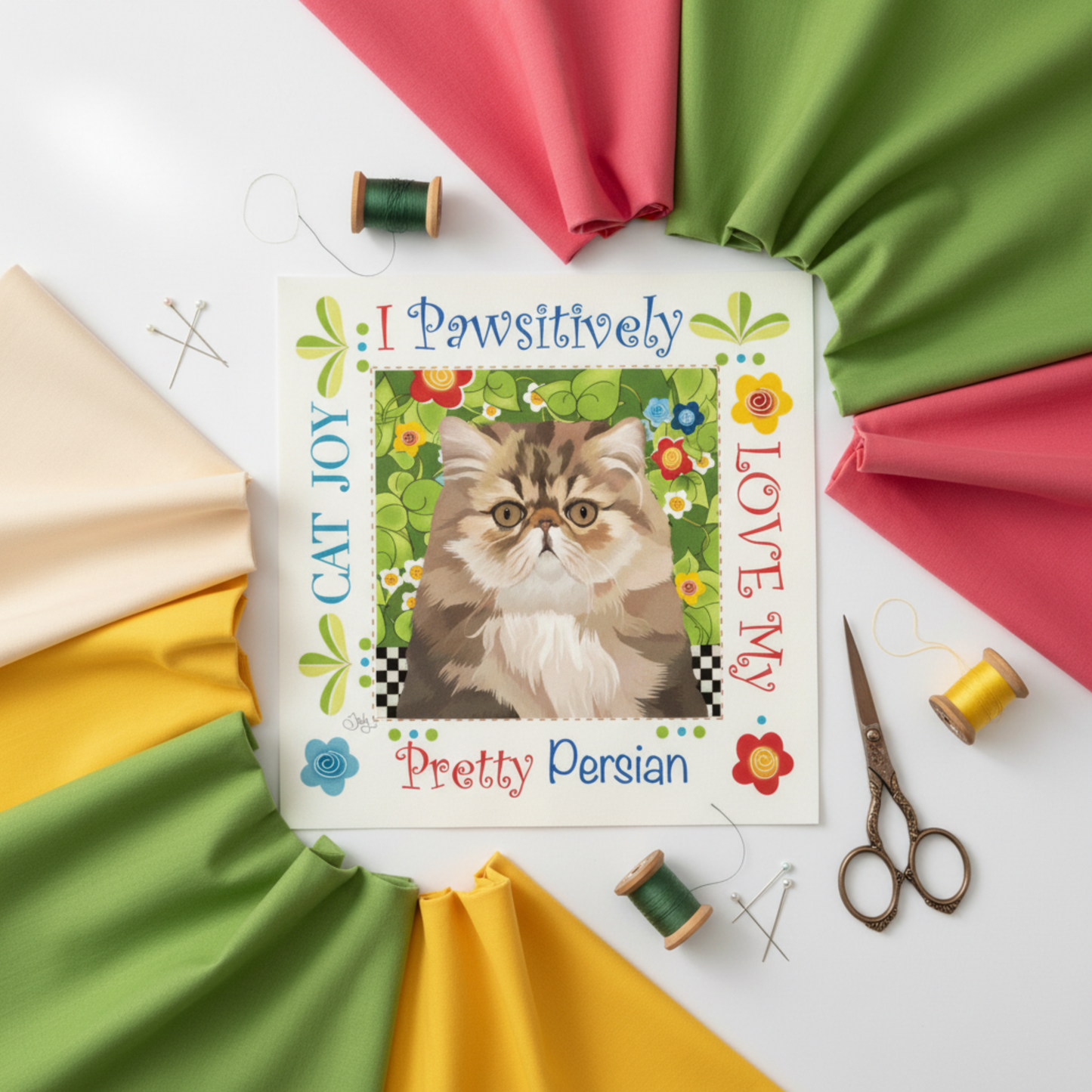 Pretty Persian Cat Joy 6" fabric art panel by Jody Houghton Designs styled with coordinating solid fabrics in pink, green, yellow and cream, vintage scissors, straight pins and green and yellow thread spools – Cat Joy collection quilt panel