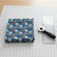 Whimsy Anemones and Berry Pods Blue quilting cotton styled on cutting mat with ruler and rotary cutter – quilt planning lifestyle