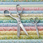 Moda 50 Years stainless steel shears and embroidery scissors on rolled quilting fabric