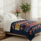Bed with a colorful floral quilt and white pillows in a bright bedroom.