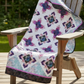 Quilt with a floral pattern draped over a wooden chair outdoors.