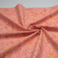 Expressions Batiks Hand-Dyed Sunset quilting cotton fabric by Riley Blake Designs – warm coral pink, golden yellow, and peach hand-dyed batik in soft folds on light grey background emphasizing texture and drap