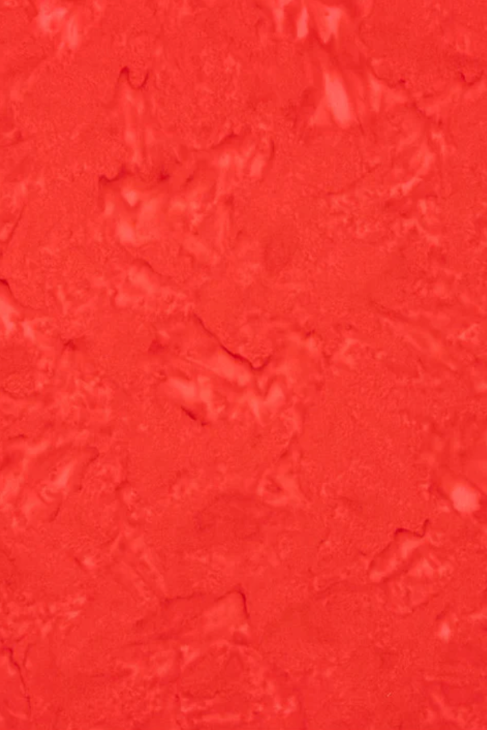 Close-up texture detail of Expressions Batiks Hand-Dyes Tomato Red quilting cotton fabric by Riley Blake Designs showing bold vivid tomato red tonal hand-dyed batik with subtle lighter rose highlights and deeper crimson organic mottled variation – organic painterly batik texture, 100% cotton, 43–44" wide