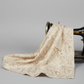Expressions Batiks Breathe Ecru quilting cotton fabric by Riley Blake Designs – draped over vintage black treadle sewing machine showing natural drape and movement, warm cream and ecru tonal batik with pine needle and feathery frond motif in soft taupe and golden-beige, light grey background