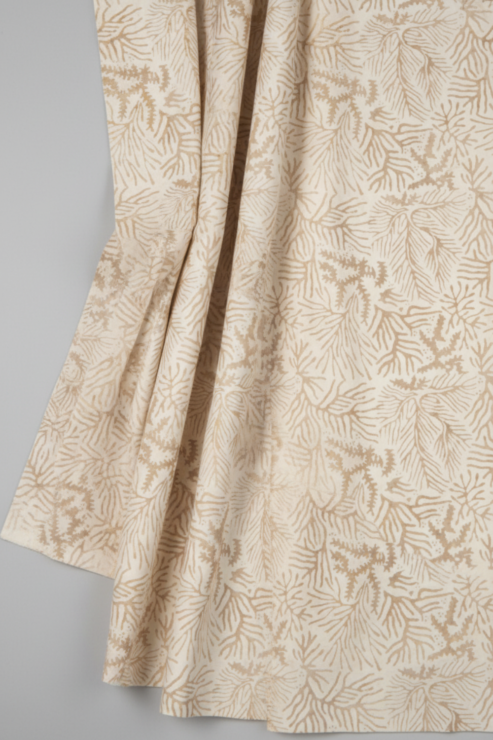 Expressions Batiks Breathe Ecru quilting cotton by Riley Blake Designs – Pinterest drape shot, soft gathered folds filling portrait frame showing natural drape and movement, warm cream and ecru tonal batik with pine needle and feathery frond motif in soft taupe and golden-beige, light grey background