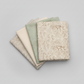 Expressions Batiks Breathe Ecru quilting cotton by Riley Blake Designs – coordination fan stack of 4 folded fabrics fanned on light grey background: cream ecru pine needle batik on top, soft sage green tonal batik, solid warm cream, and taupe-grey small geometric batik on bottom
