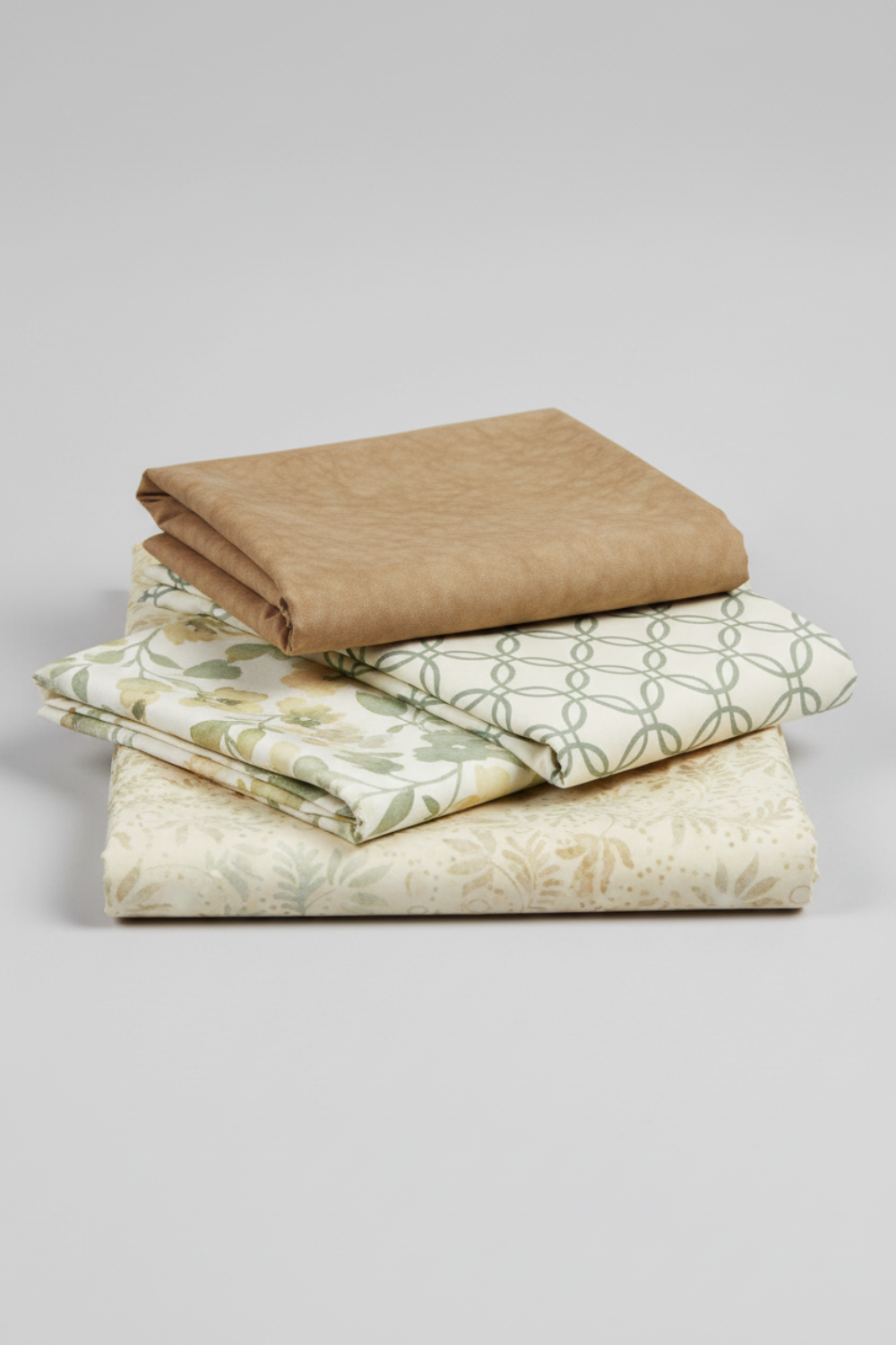 Expressions Batiks Breathe Laurel quilting cotton by Riley Blake Designs – Pinterest coordination stack of 4 folded fabrics stacked on light grey background: warm tan solid batik on top, cream and sage green interlocking circles geometric, cream sage green floral vine print, and cream ivory large floral batik on bottom