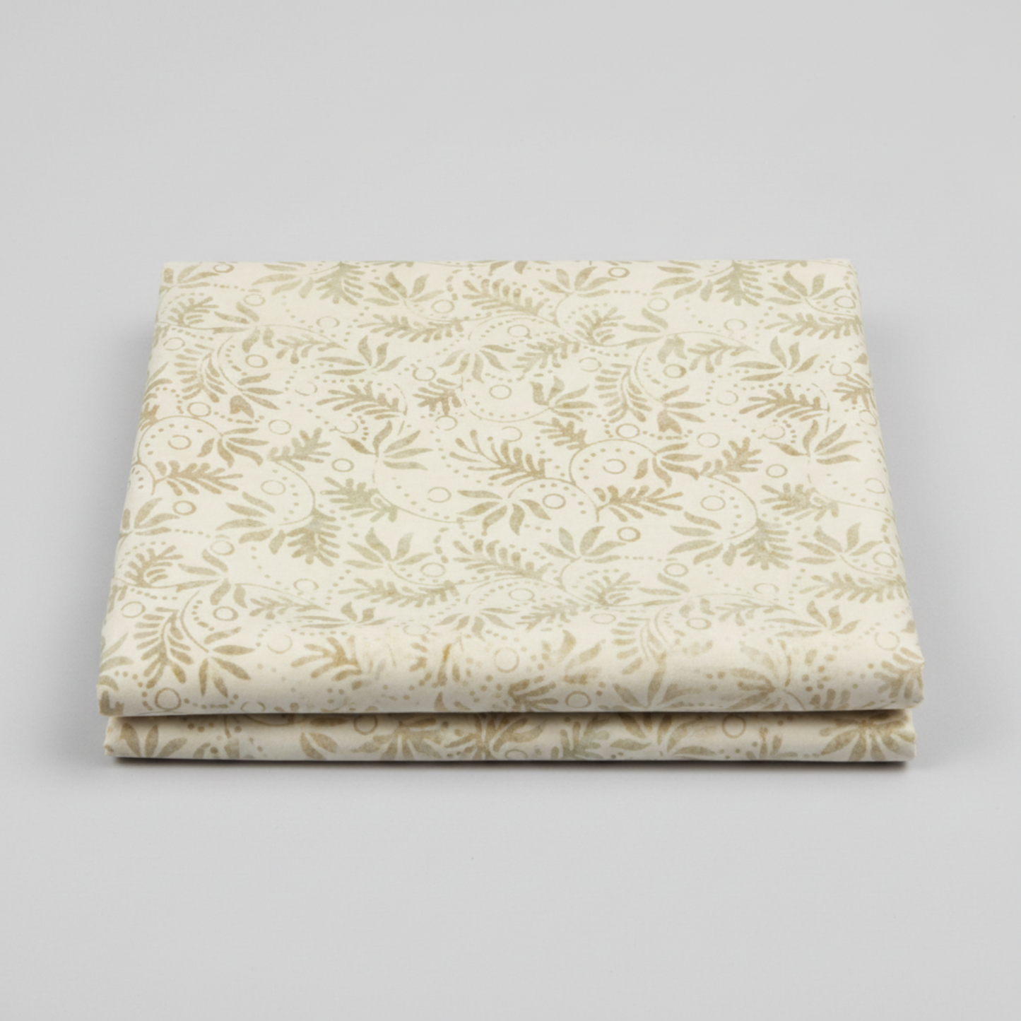 Expressions Batiks Breathe Laurel quilting cotton fabric by Riley Blake Designs – 2 neatly folded yards stacked on light grey background showing cream and ivory tonal batik with feathery fronds, dotted circular swirl outlines, and tiny leaf sprigs in soft sage green and warm taupe