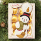 Snowman candle ornament packaging on a green leaf background