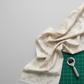 Expressions Batiks Breathe Flaxen by Riley Blake Designs – cream batik fabric loosely gathered on light grey surface with green cutting mat and rotary cutter, showing natural drape and soft hand in quilting workspace setting