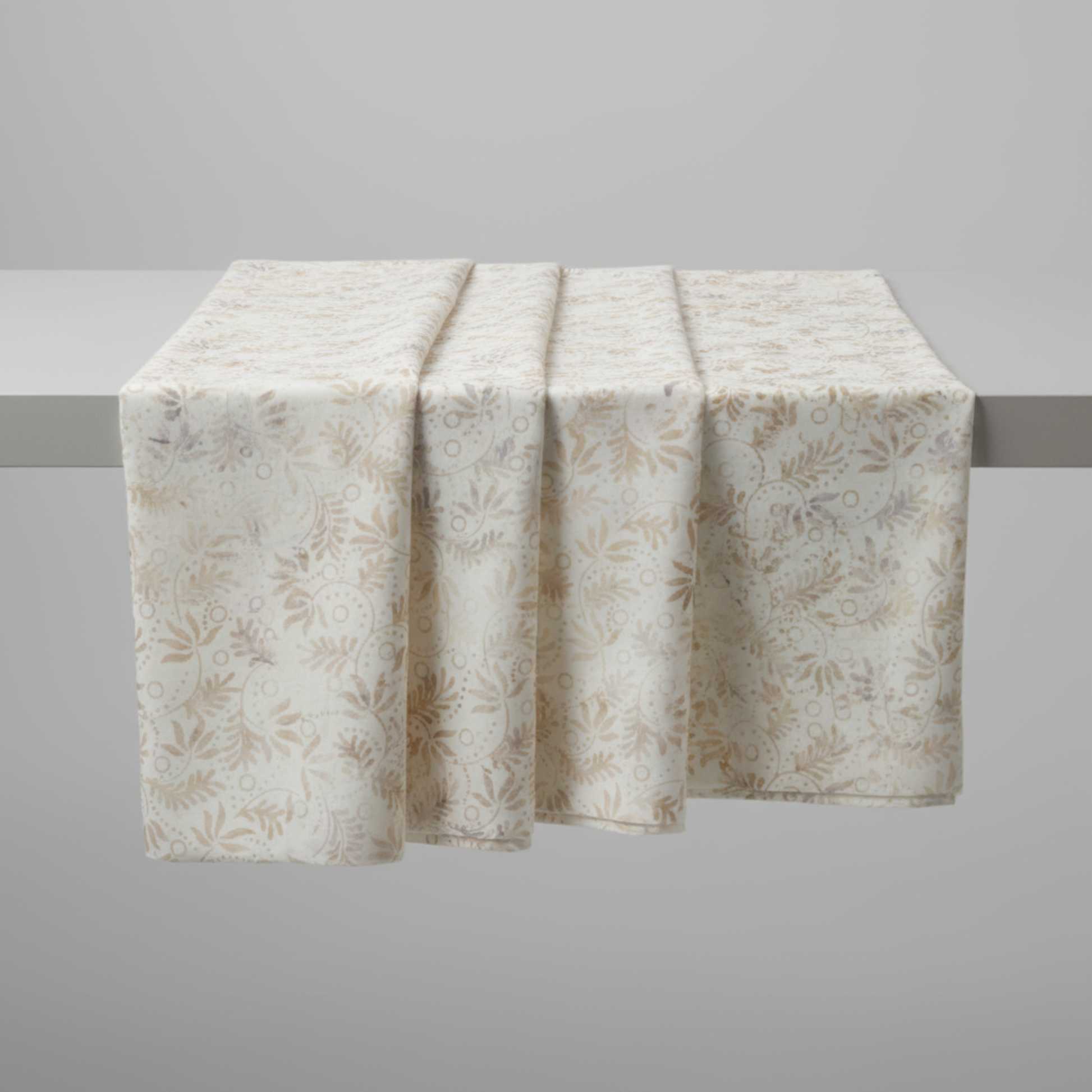 Expressions Batiks Breathe Flaxen by Riley Blake Designs – fabric draped in soft pleated folds over a horizontal bar on light grey background showcasing natural drape and luminous cream batik with swirling vine and feathery leaf pattern