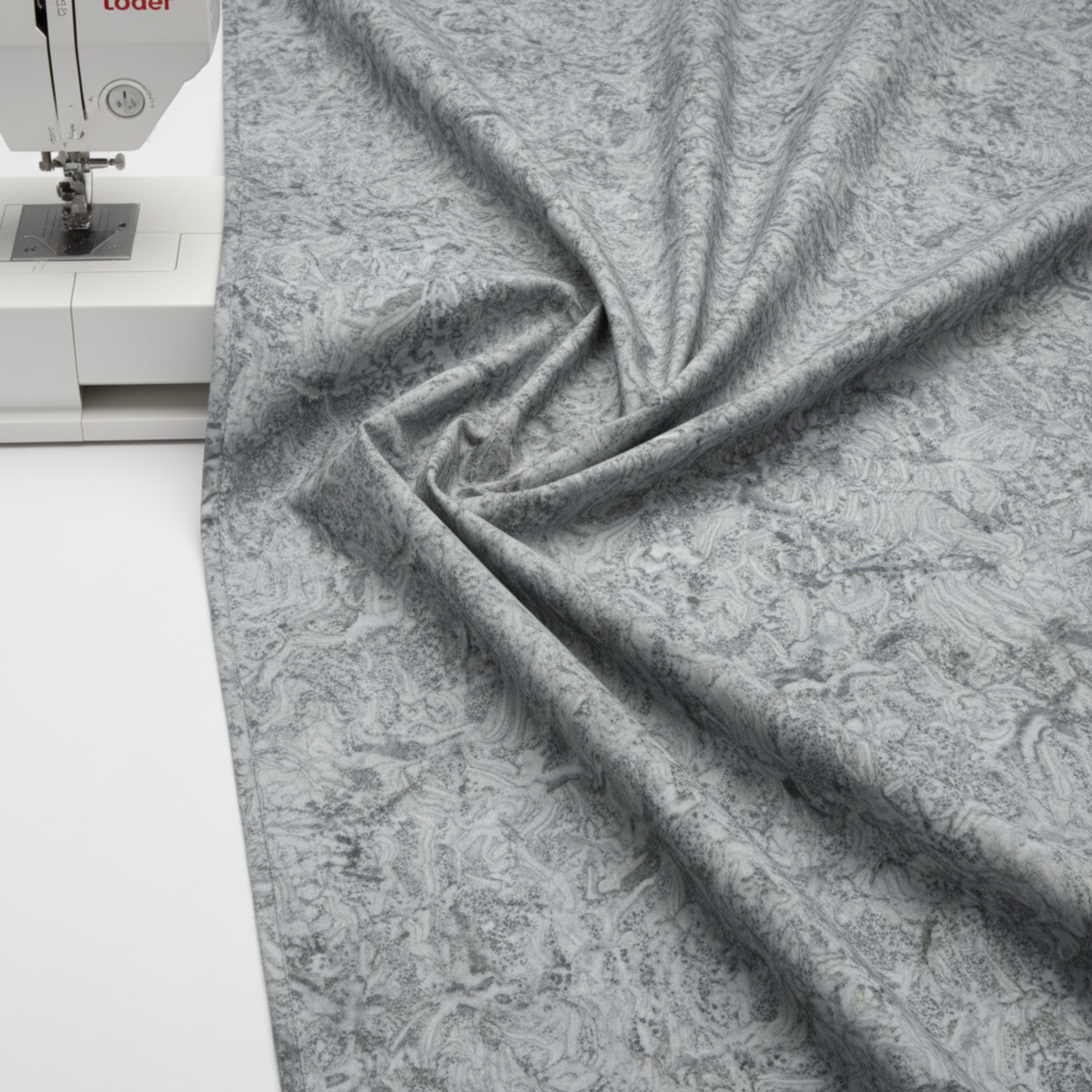 Expressions Batiks Hand-Dyed Charcoal – fabric draped over edge of sewing machine showing charcoal hand-dyed batik texture and drape