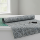 Expressions Batiks Hand-Dyed Charcoal – fabric with soft folds on quilting room table, edge of cutting mat and rotary cutter visible