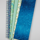 Six coordinating quilting fabrics including Hand-Dyed Ocean Blue fanned in complementary ocean and teal tones
