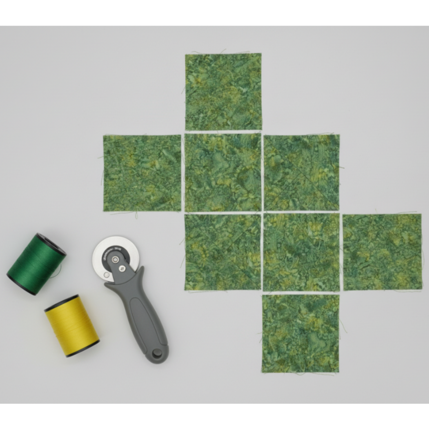 Expressions Batiks Hand-Dyed Amazon quilting cotton fabric by Riley Blake Designs – jungle green batik cut into squares for quilting project on light grey background