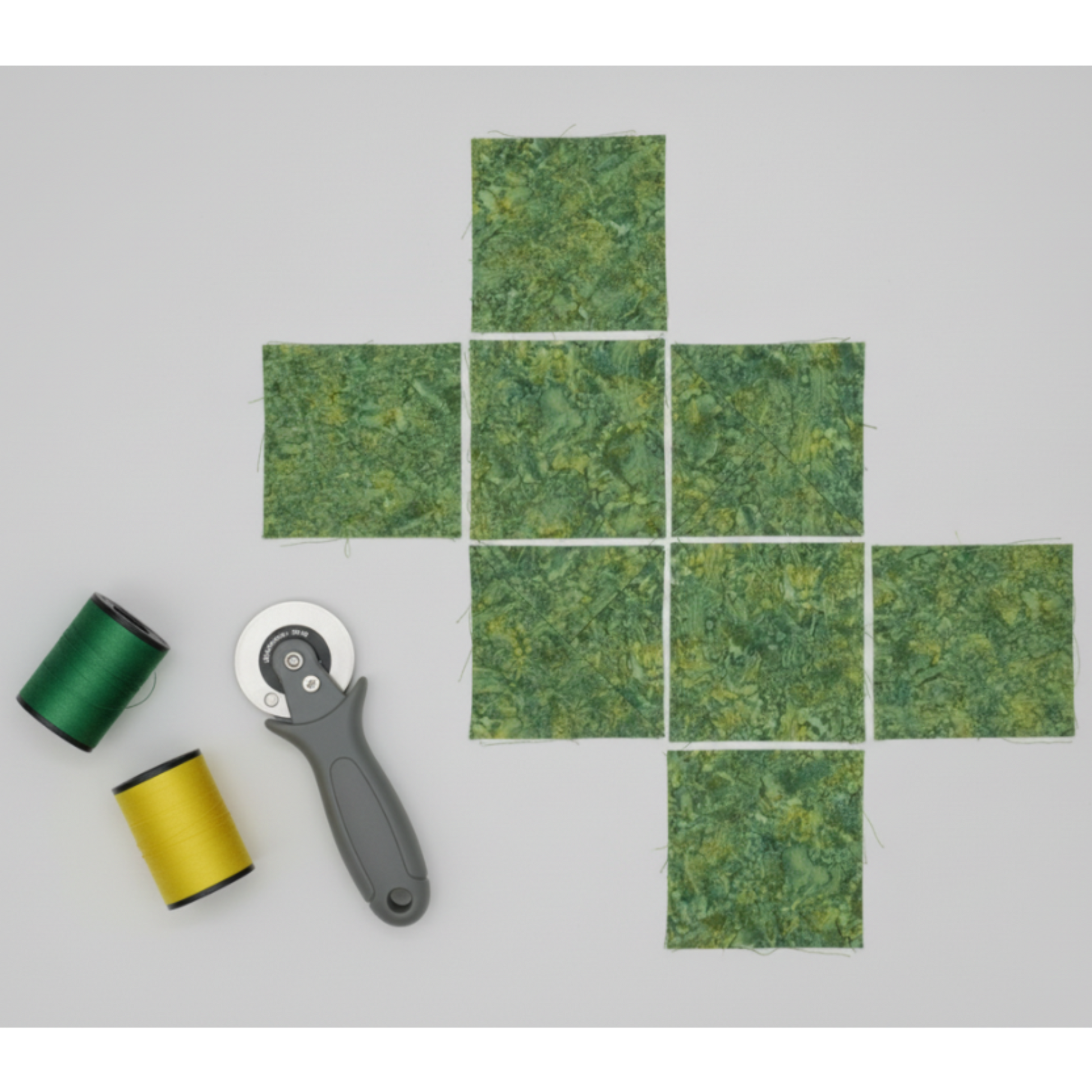 Expressions Batiks Hand-Dyed Amazon quilting cotton fabric by Riley Blake Designs – jungle green batik cut into squares for quilting project on light grey background