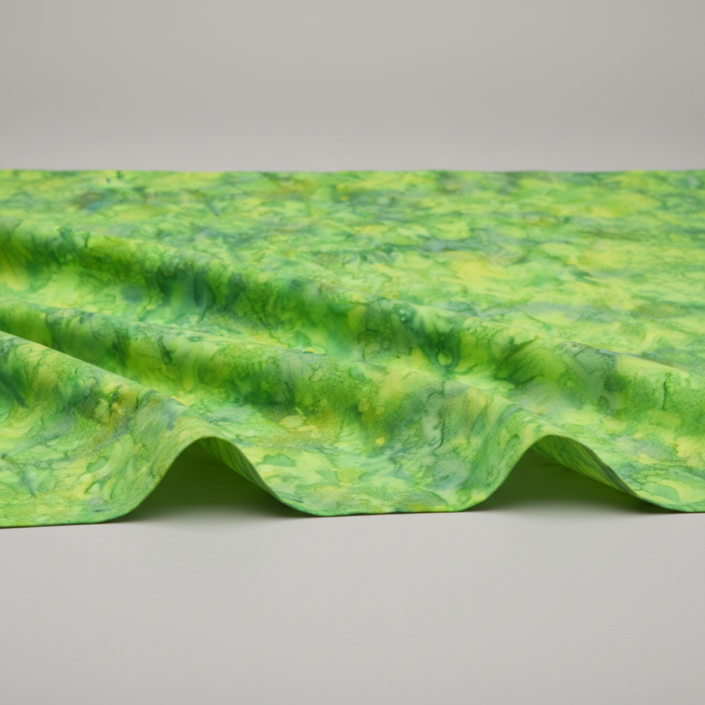 Expressions Batiks Hand-Dyed Shamrock quilting cotton draped over a flat surface with soft folds to show softness and movement