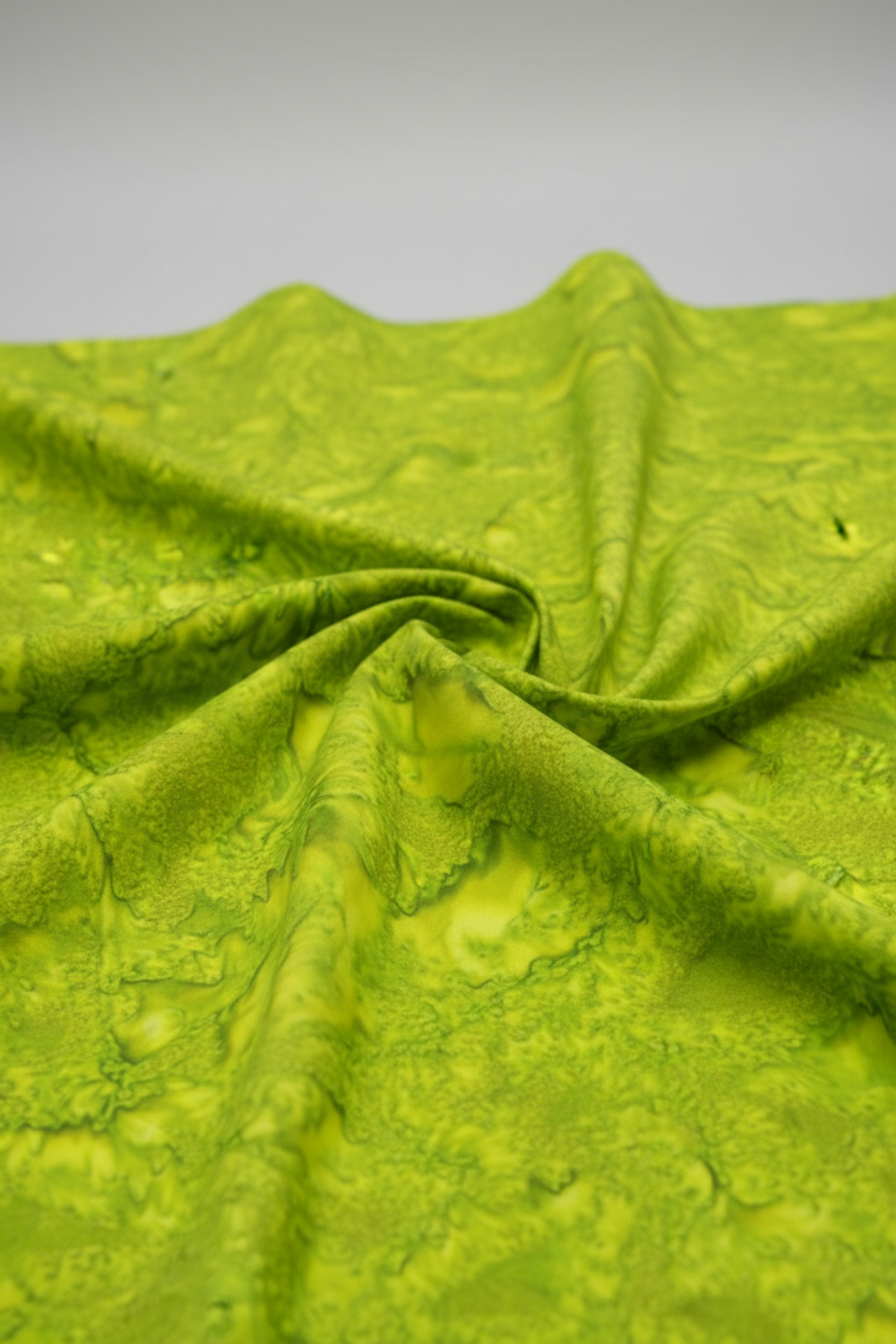 Expressions Batiks Hand-Dyed Sap quilting cotton fabric by Riley Blake Designs – vivid chartreuse yellow-green hand-dyed batik in soft folds on flat surface showing texture and tonal variation