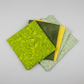 Expressions Batiks Hand-Dyes quilting cotton fabrics including Sap – 5 coordinating fabrics in complementary green and yellow tones slightly fanned on light grey background