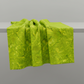 Expressions Batiks Hand-Dyed Sap quilting cotton fabric by Riley Blake Designs – vivid sap green hand-dyed batik draped over table edge with natural soft folds on light grey background