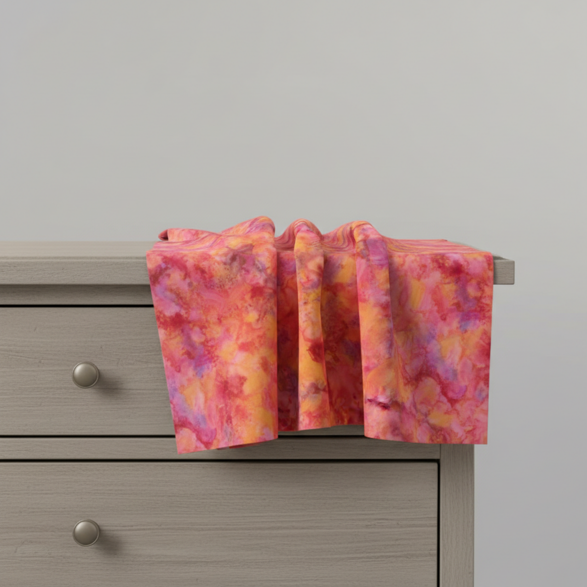 Expressions Batiks Hand-Dyed Bouquet quilting cotton fabric by Riley Blake Designs – vibrant golden orange and pink multicolor hand-dyed batik draped over edge of table showing natural drape and movement