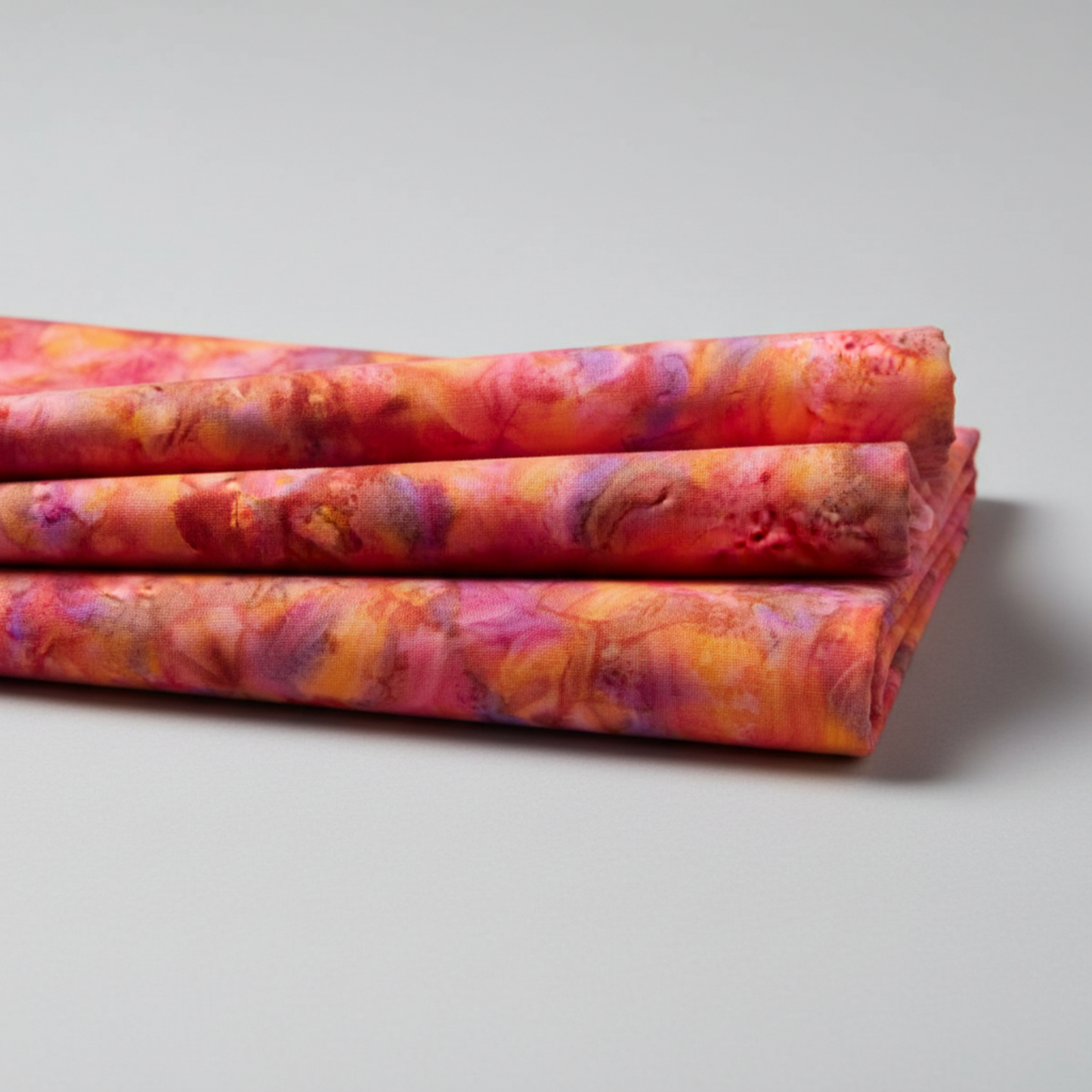 Expressions Batiks Hand-Dyed Bouquet quilting cotton fabric by Riley Blake Designs – vibrant multicolor hand-dyed batik arranged in 3–5 soft natural folds on flat surface showing drape and softness