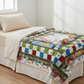 Colorful quilt with bright vehicles, animals on a bed in a bright room