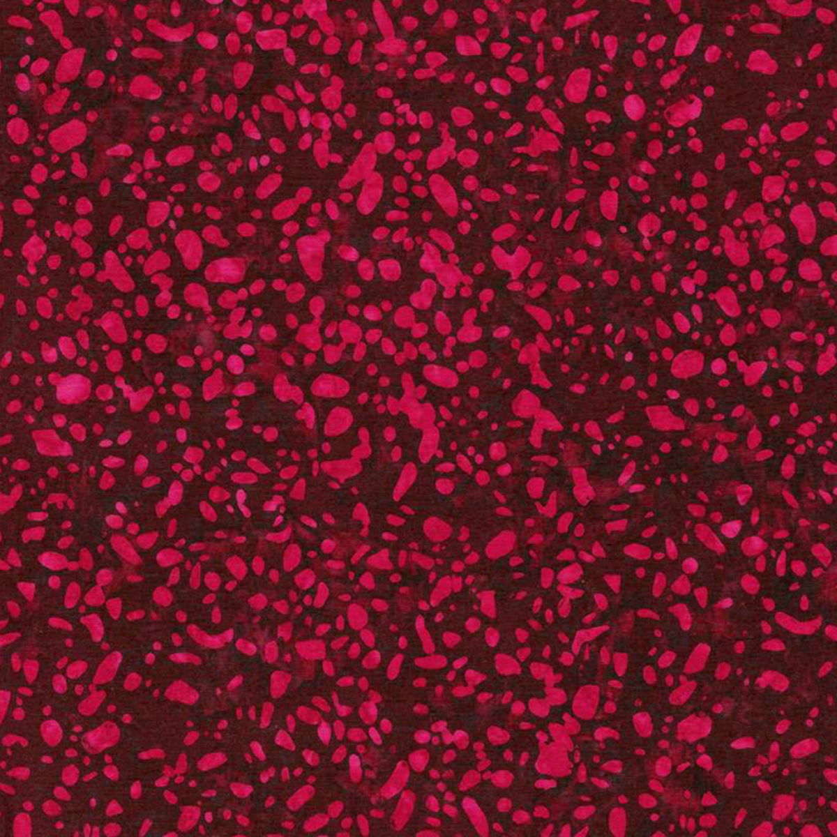 Close-up of Terrazzo Mahogany batik fabric by Riley Blake Designs, with raspberry-magenta pebble-shaped speckles on a mottled deep burgundy ground