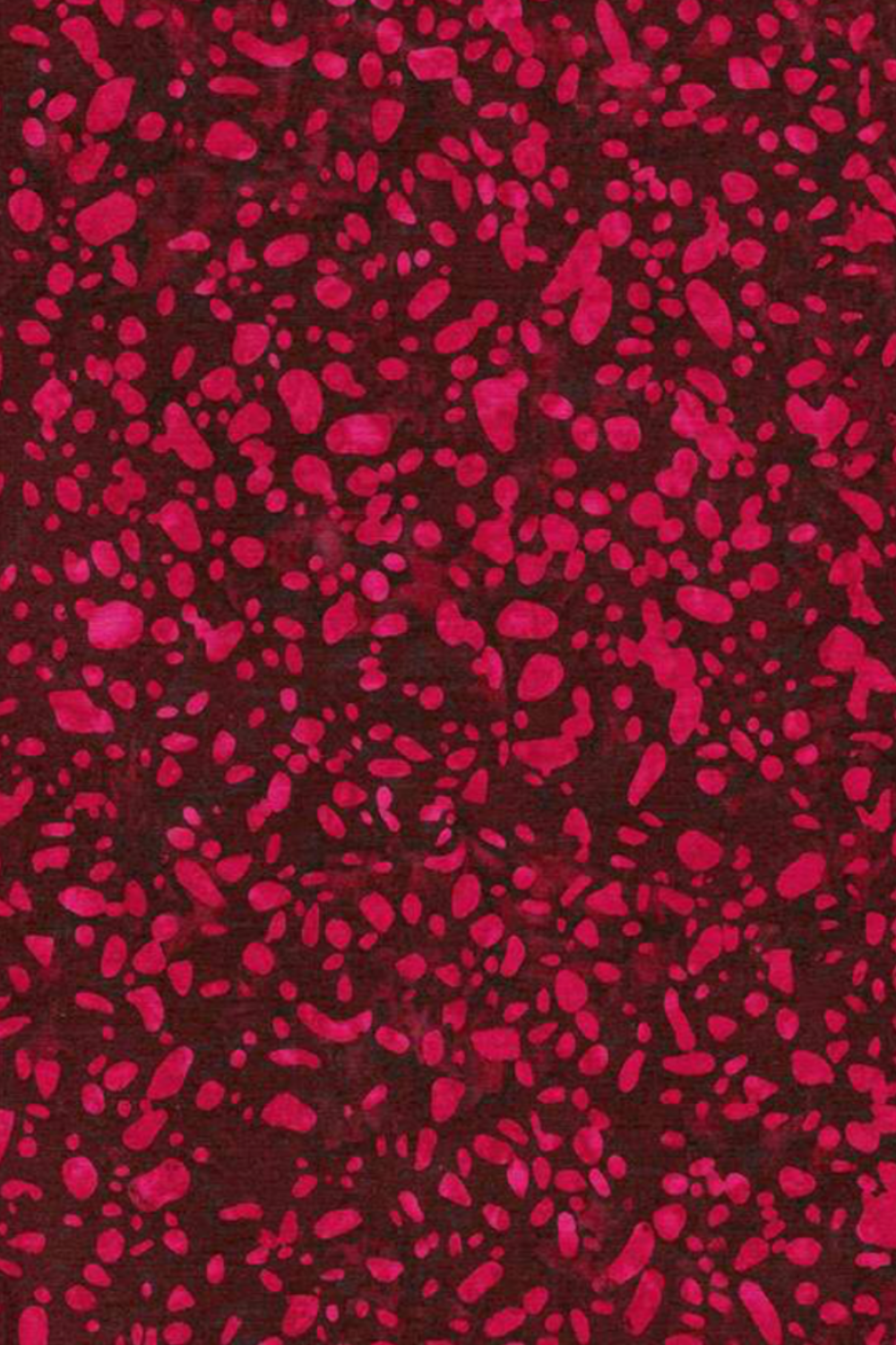 Close-up of Terrazzo Mahogany batik fabric by Riley Blake Designs, showing raspberry-magenta pebble-shaped speckles on a mottled deep burgundy ground.