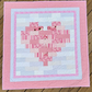 Quilt with pink heart pattern on a wooden surface