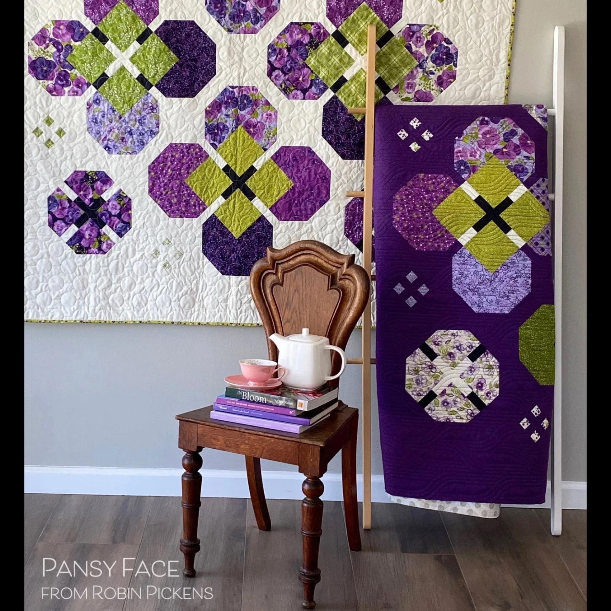 Pansy Face quilt pattern room setting — lap quilt on wall and purple queen quilt on ladder with vintage chair and tea set by Robin Pickens
