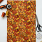 Autumn Celebration Multi Small Foliage quilting cotton styled on cutting mat with quilting tools – lifestyle shot for quilters