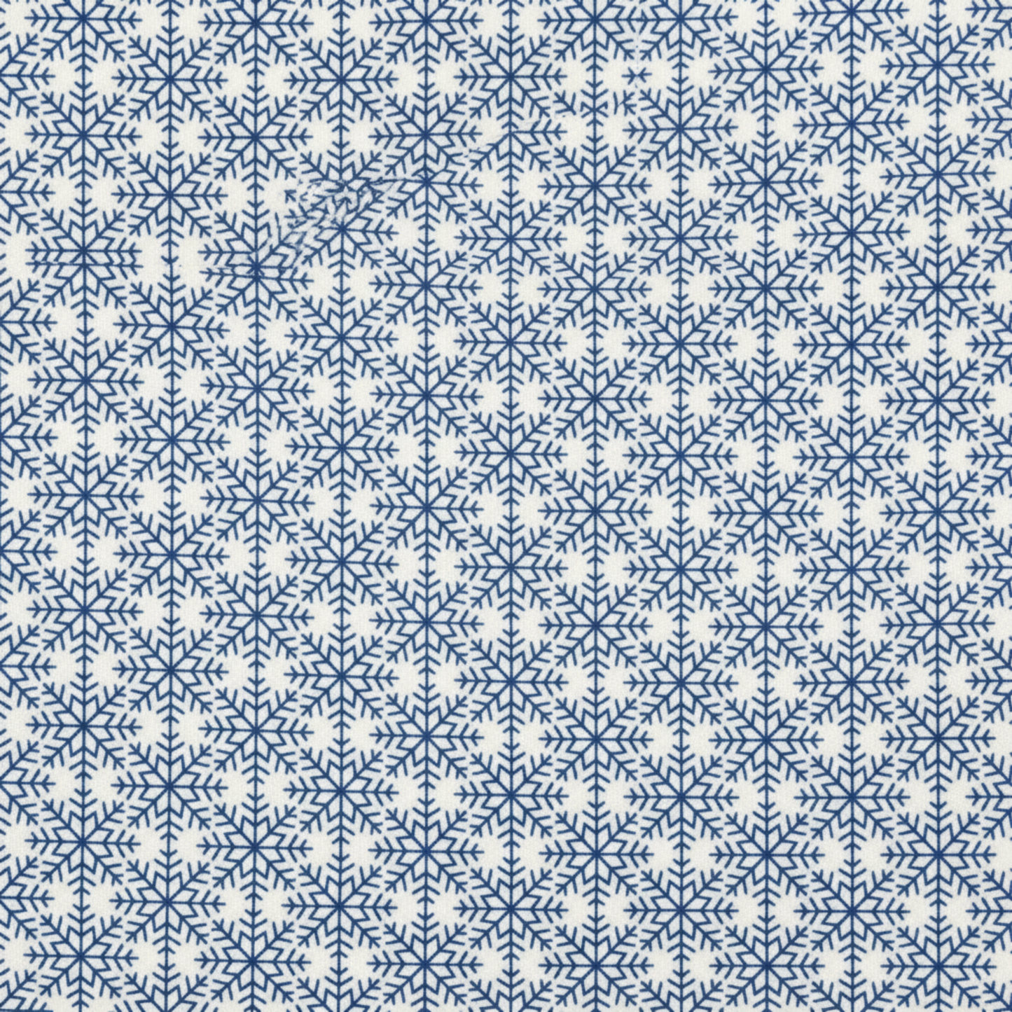 Close-up of NYSNO Blue Snowflake Grid quilting cotton showing detailed blue snowflakes in geometric layout
