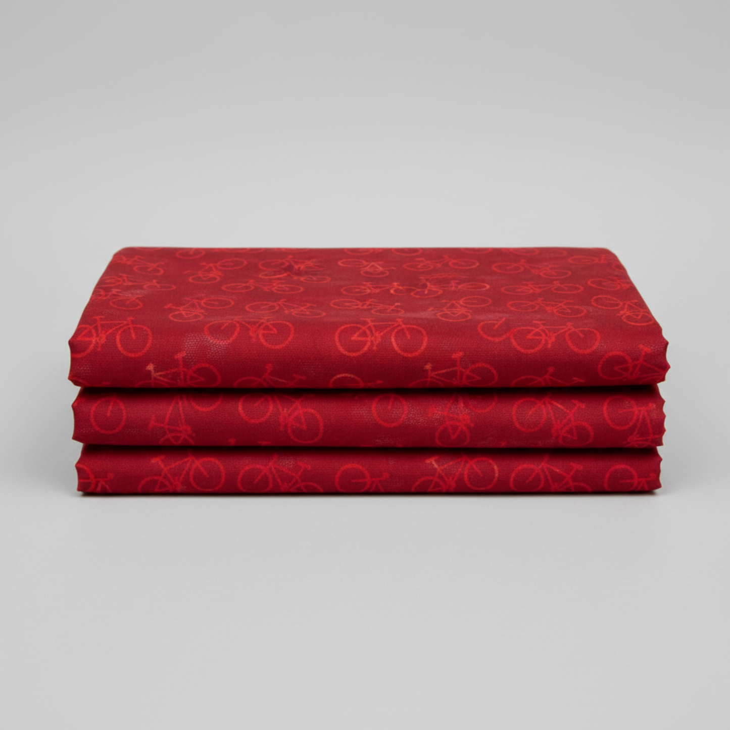 On the Go Bicycles Red quilting cotton folded stack showing fabric body and drape quality