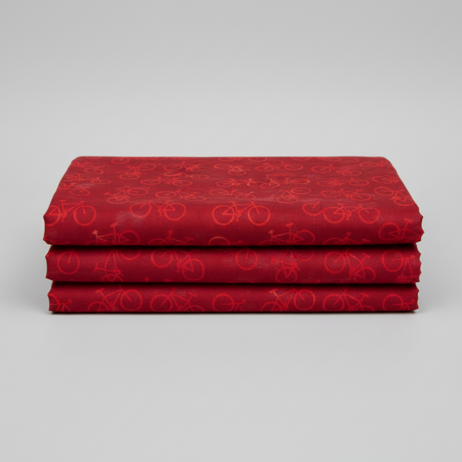 On the Go Bicycles Red quilting cotton folded stack showing fabric body and drape quality