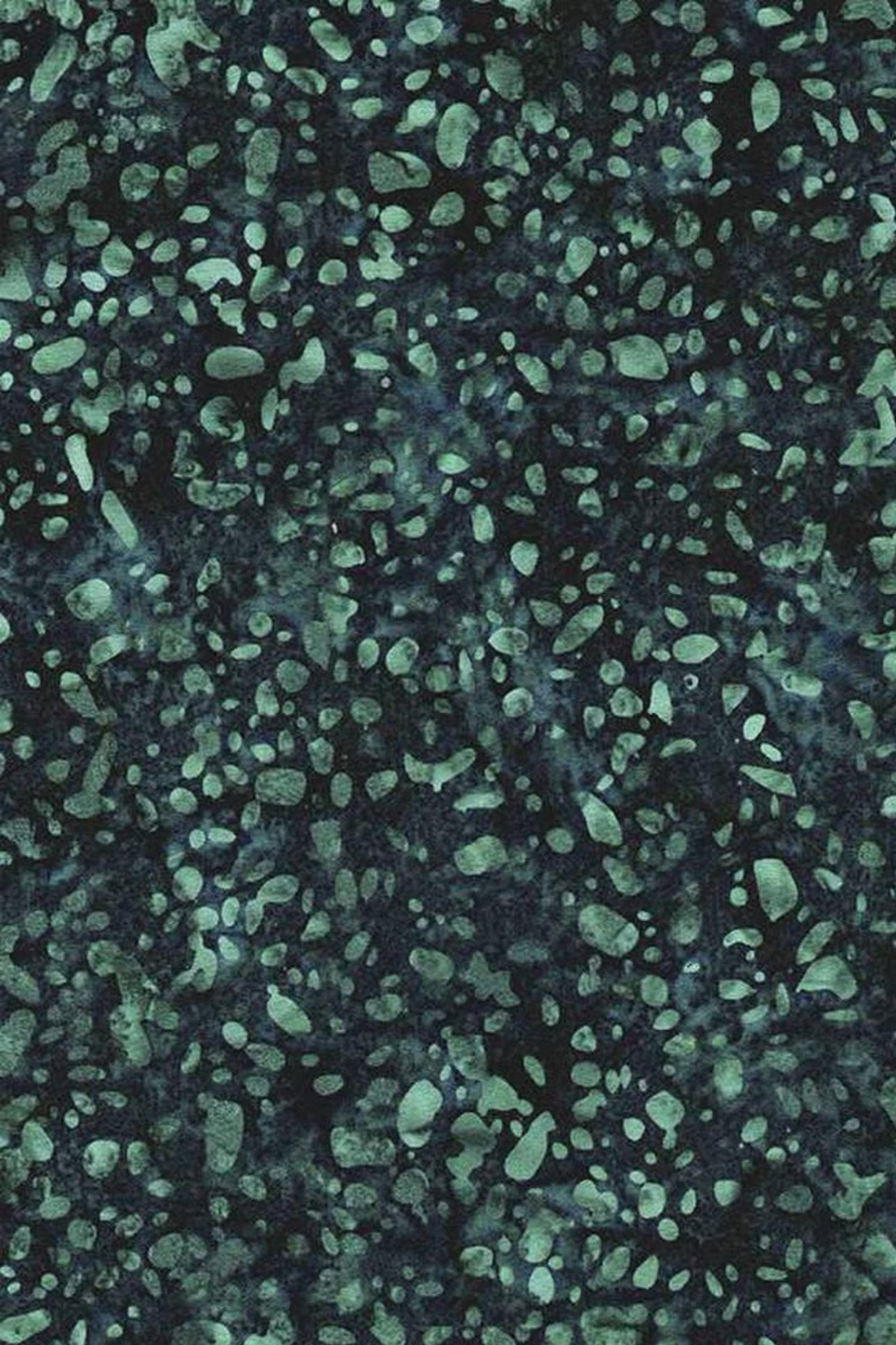Close-up of Terrazzo Smoky Teal batik fabric by Riley Blake Designs, with soft teal pebble-shaped speckles on a mottled dark navy-teal ground.