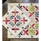 Criss Cross Kisses quilt pattern overhead flat lay by Robin Pickens — crimson and navy colorway alongside green and pink colorway, showing X blocks and arrowhead sashing on cream background
