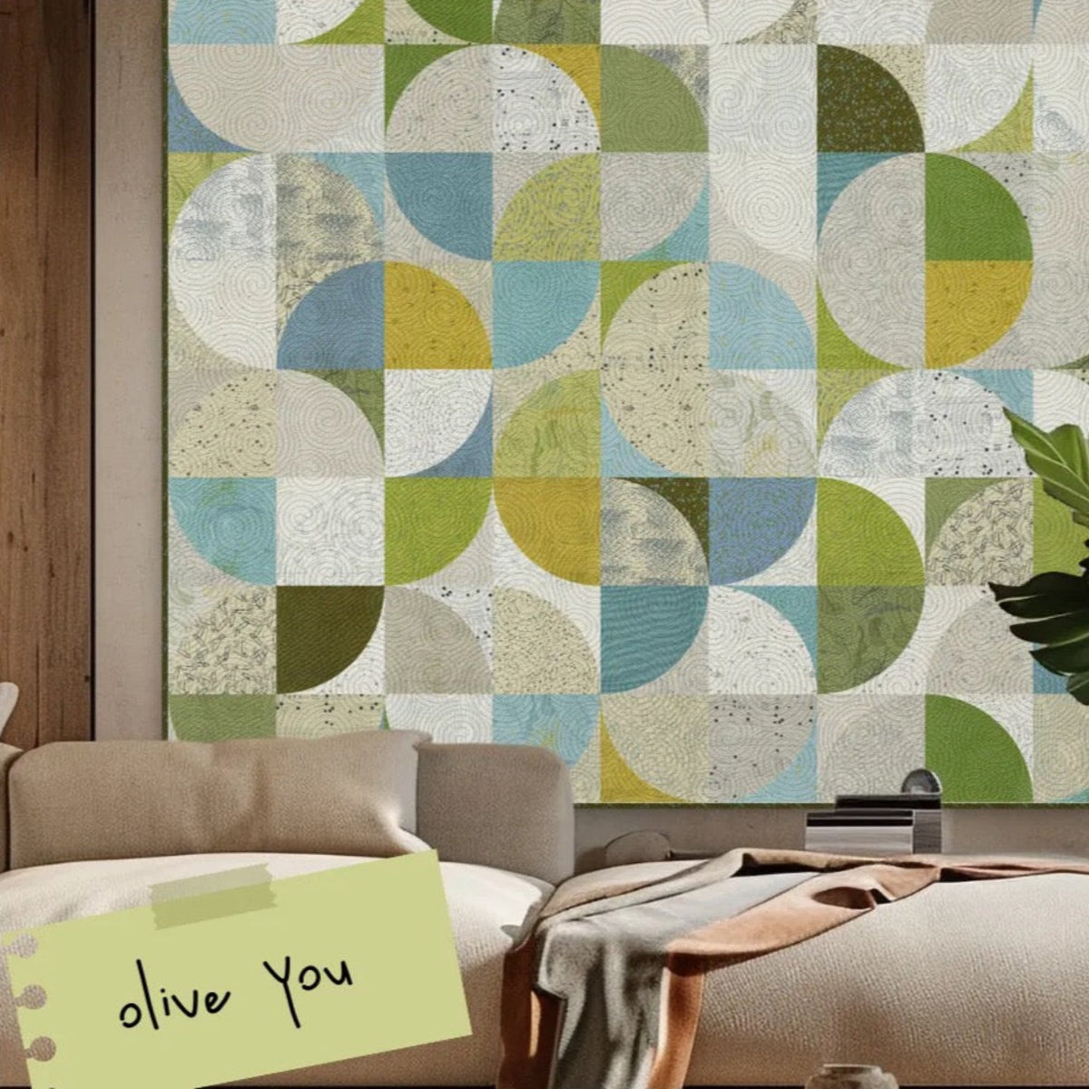 Finished geometric quilt in cream, aqua, green, and yellow Olive You prints displayed above a sofa. Quilt shown for inspiration; coordinating fabrics and quilt patterns are available at IraRobi Quilts.