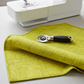 Interwoven Citron quilting cotton fabric from the Interwoven collection, bright citron yellow-green geometric draped beside sewing machine to show soft drape and scale