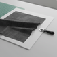 Interwoven Dark Slate by Jason Yenter – quilt room lifestyle flat lay with folded fabric, cutting mat, and rotary cutter on light grey base