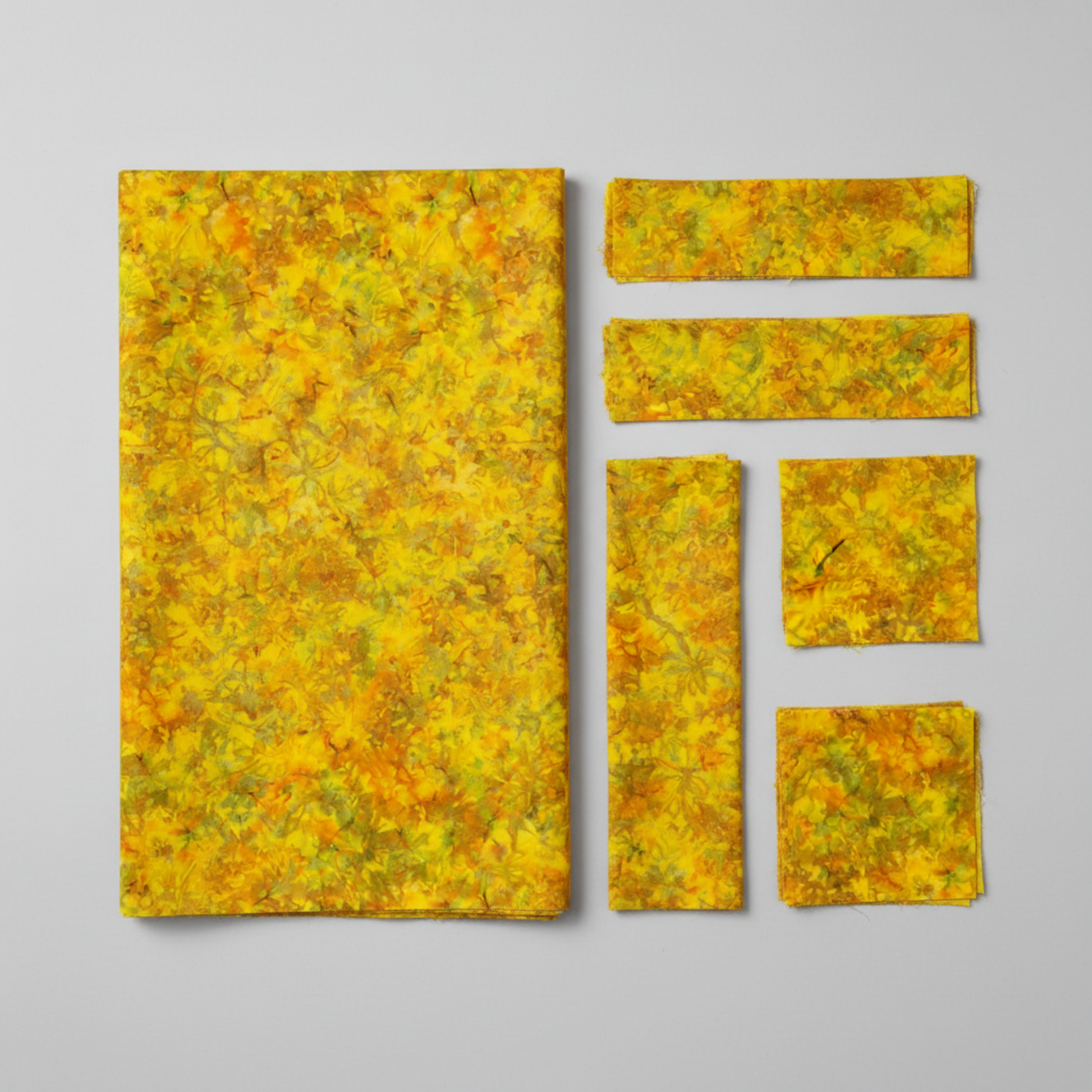 Expressions Batiks Hand-Dyed Yellow Orange Multi III quilting cotton fabric by Riley Blake Designs – overhead view of vivid multicolor hand-dyed batik with cut strips and squares in clean organized layout, light grey background