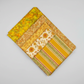 Expressions Batiks Hand-Dyed Yellow Orange MultiIII quilting cotton by Riley Blake Designs – coordination stack of 5 fanned warm-toned quilting fabrics including yellow-orange multicolor batik, golden floral tonal, cream sunflower print, mustard yellow solid, and olive green stripe on light grey background