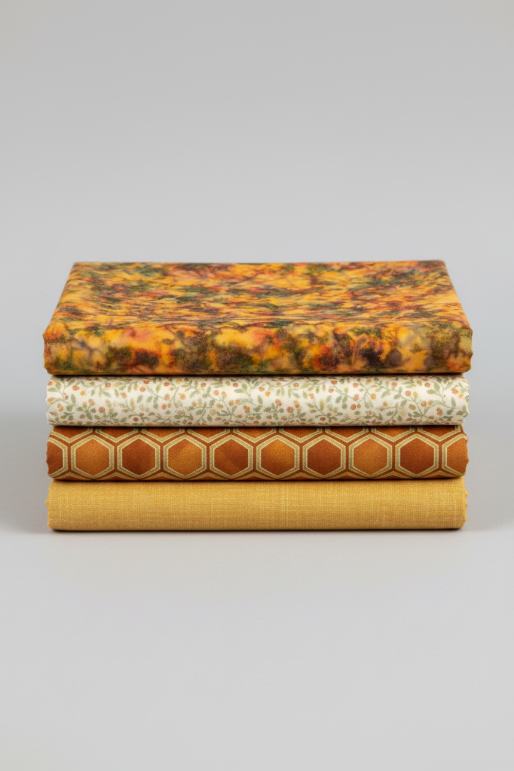 Expressions Batiks Hand-Dyed Orange Multi I quilting cotton by Riley Blake Designs – Pinterest coordination stack of 4 folded fabrics stacked vertically on light grey background: amber-orange multicolor batik on top, cream small floral vine print, rust orange hexagon geometric, and golden mustard yellow solid