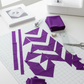 Interwoven Plum by Jason Yenter – Pinterest overhead quilt-in-progress layout with cut strips and HSTs, ruler, scissors, and corner of sewing machine visible, clean flat lay