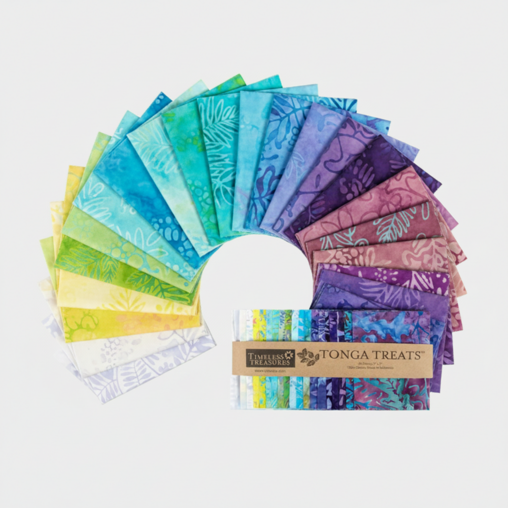 Tonga Batik Dreamer by Timeless Treasures – 42 pre-cut 5" charm squares fanned in full color arc on light grey background with Tonga Treats package, showing complete palette from white and yellow through aqua, teal, blue, lavender, purple, and mauve